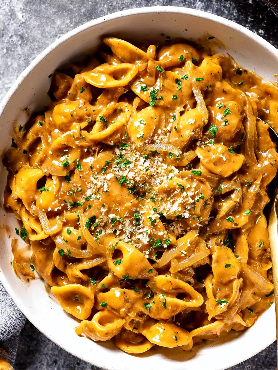 A bowl of pasta with onions and cheese.
