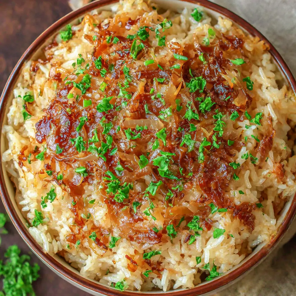 A bowl of rice with onions and parsley.