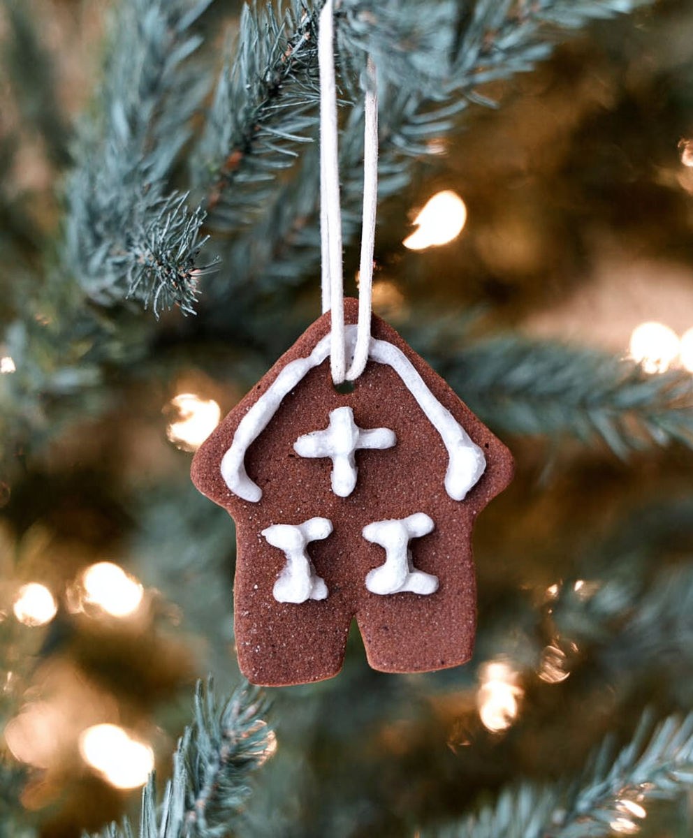 A gingerbread house ornament hanging from a tree.