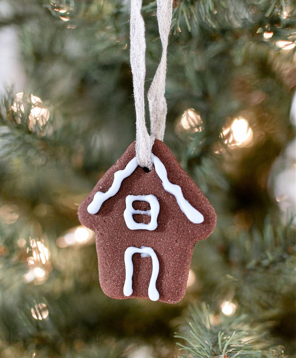 A gingerbread house ornament hangs from a tree.