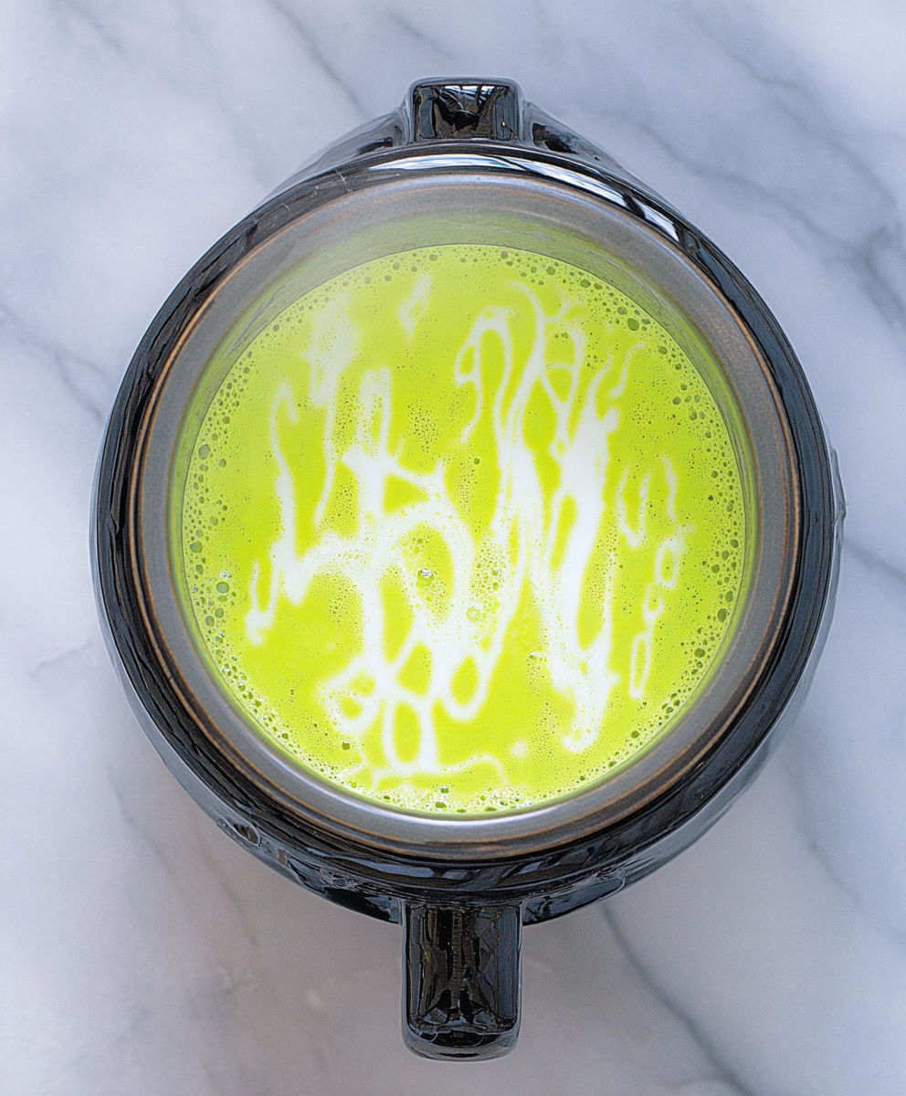A cup of green liquid with a yellow swirl.