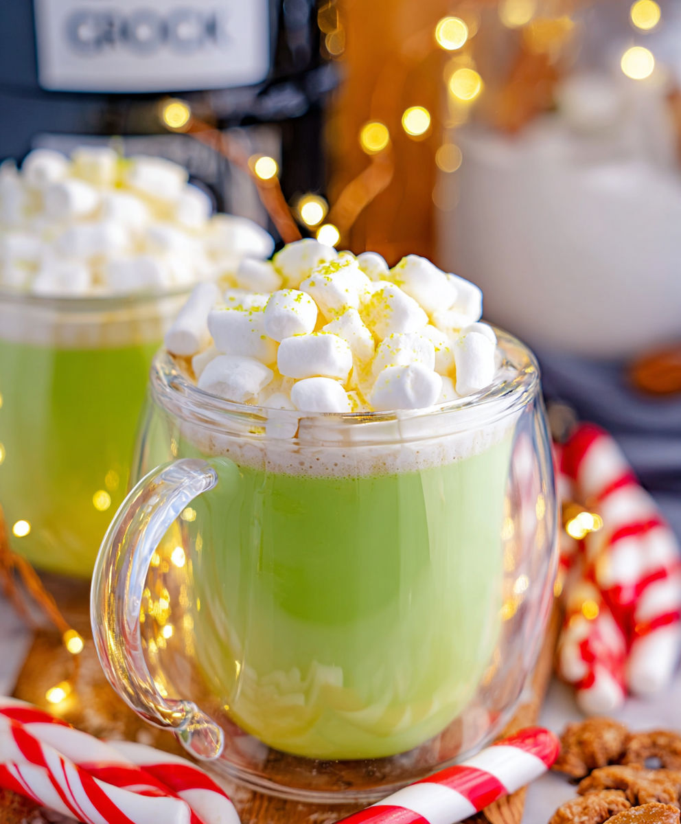 A glass of green milk with marshmallows on top.