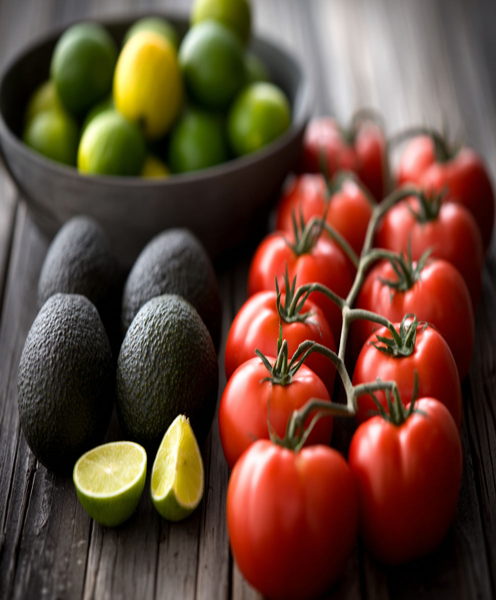 A bowl of green limes and a bowl of green tomatoes.