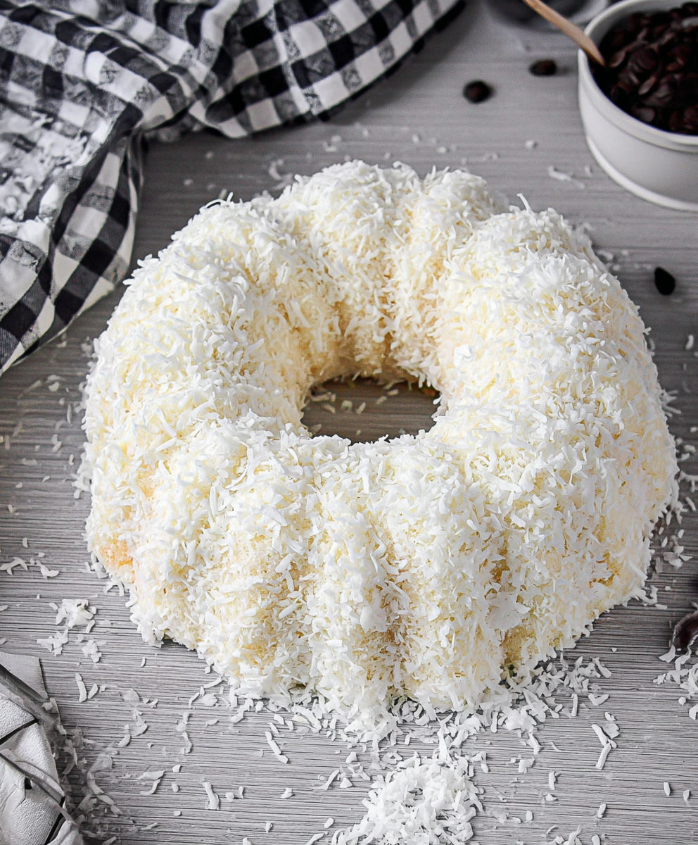 A white cake with white frosting and coconut on top.