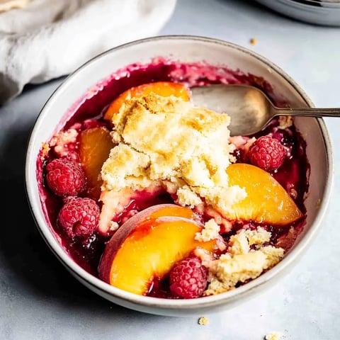 A bowl of fruit with a spoon in it.