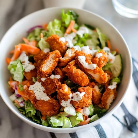 A bowl of salad with chicken and dressing.