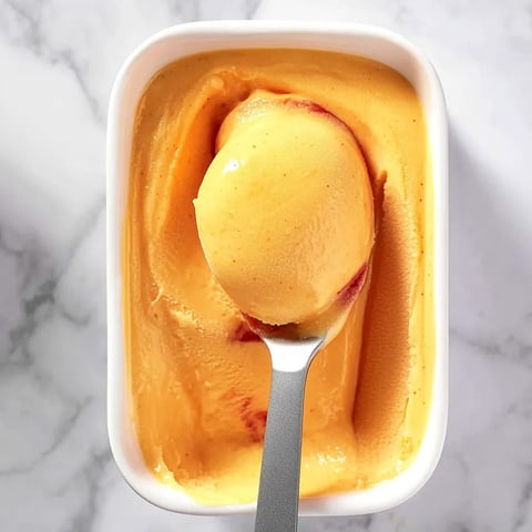 A spoon in a bowl of orange sauce.