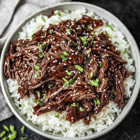 A bowl of rice with meat and green onions.