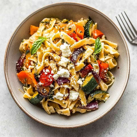 A bowl of pasta with vegetables and cheese.