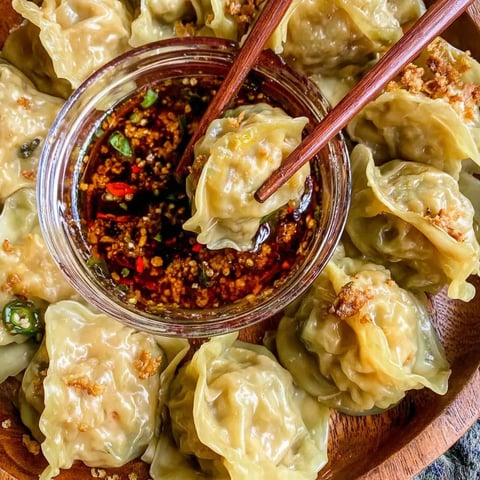 A bowl of dumplings with chopsticks in it.