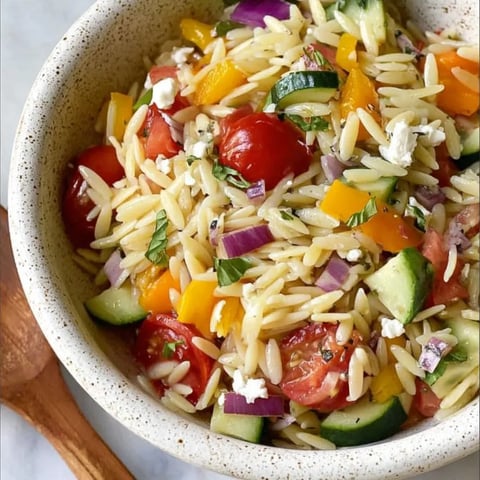 A bowl of pasta salad with tomatoes, cucumbers, and feta cheese.