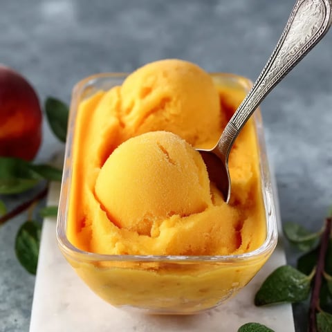 A bowl of orange ice cream with a spoon in it.