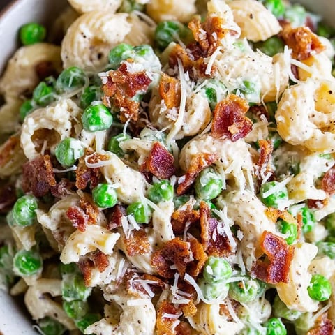 A bowl of pasta with bacon and peas.