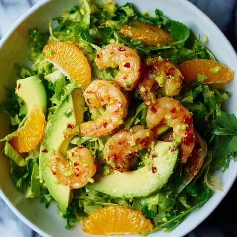 A bowl of shrimp salad with avocado and orange.