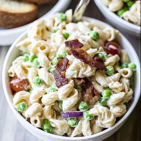 A bowl of pasta with peas and bacon.