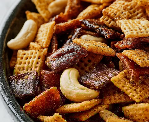 A bowl of chips with nuts and raisins.