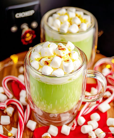 Two glasses of green drink with marshmallows on top.