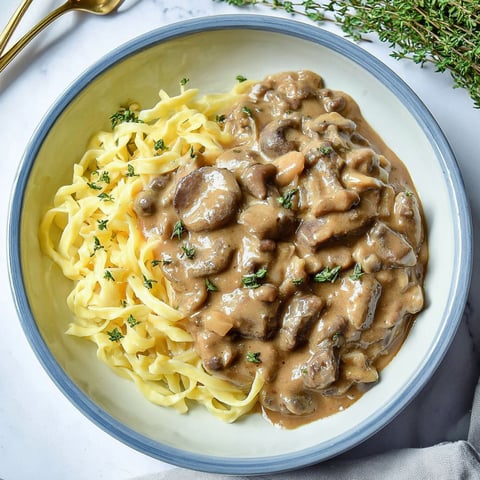 A bowl of pasta with mushrooms and sauce.