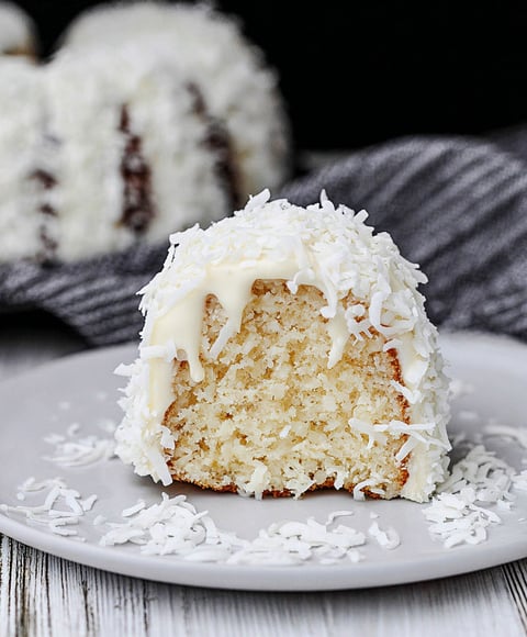 A white cake with white frosting and coconut on top.