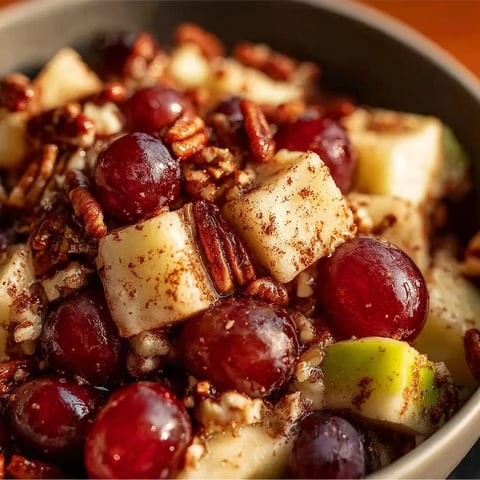 A bowl of fruit with nuts and raisins.