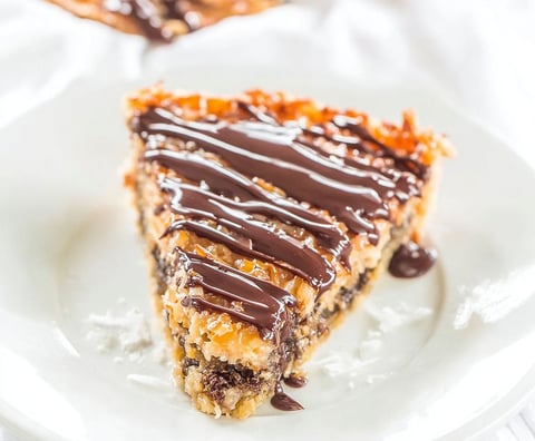 A slice of pie with chocolate drizzled on top.
