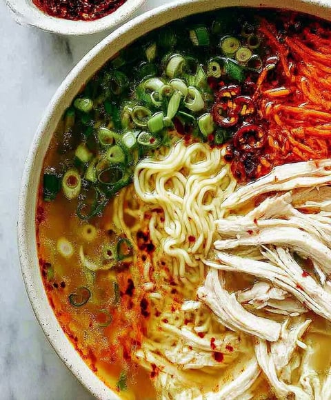 A bowl of noodles with chicken and vegetables.